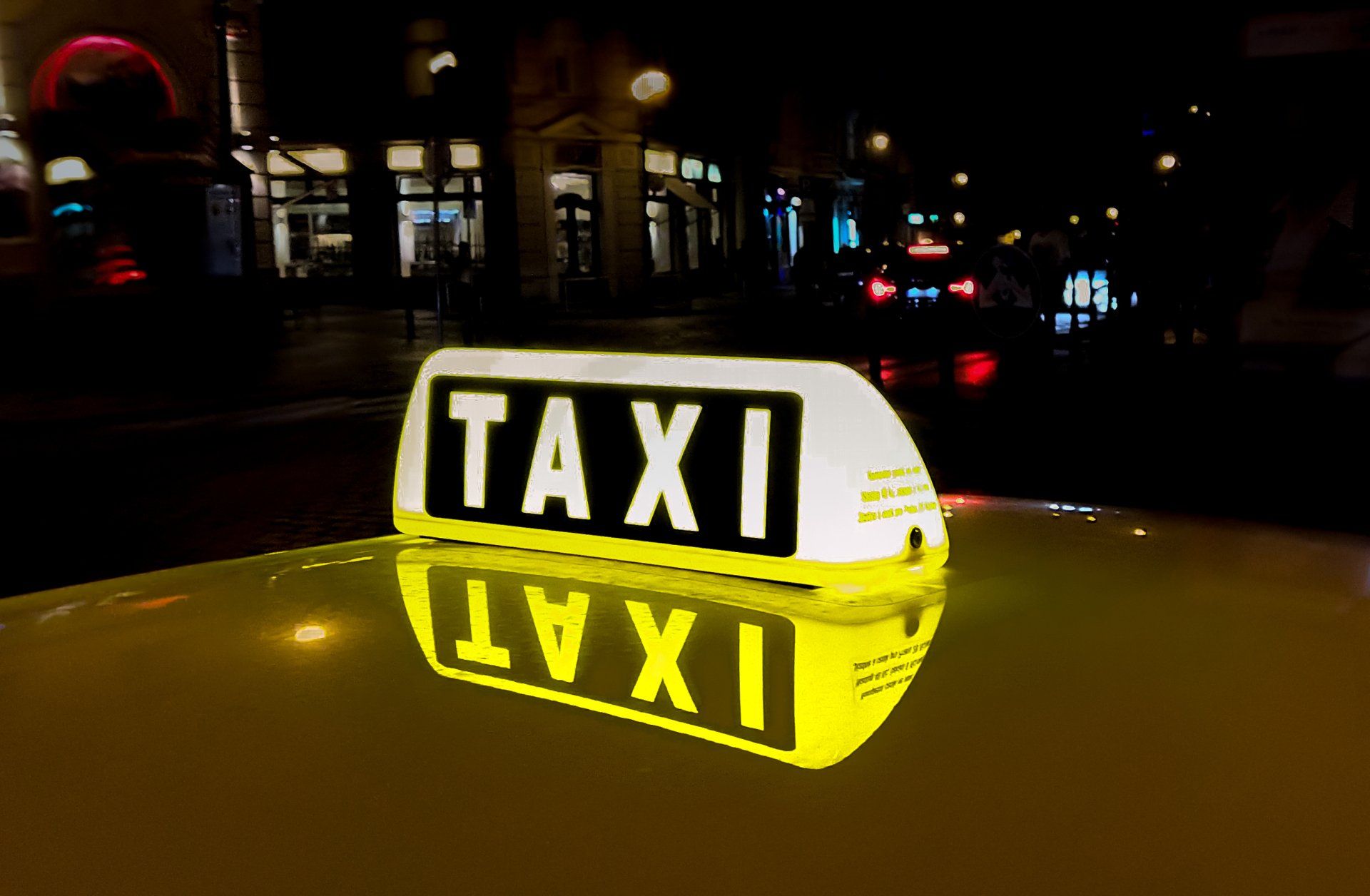 Un cartel de taxi encima de un coche por la noche.