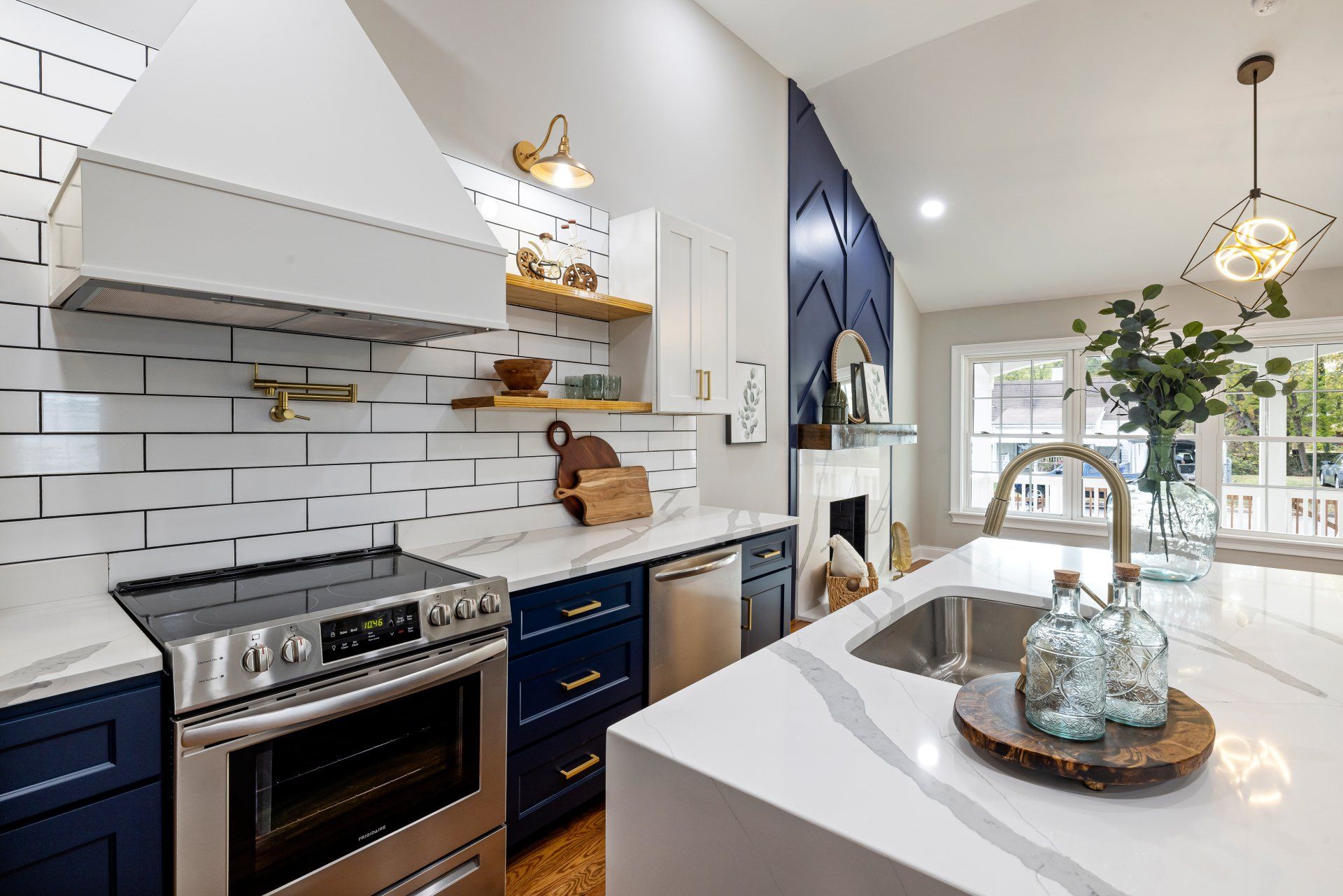 This all white kitchen boasts a clean modern look. The gold pot filler is mounted above the stove.