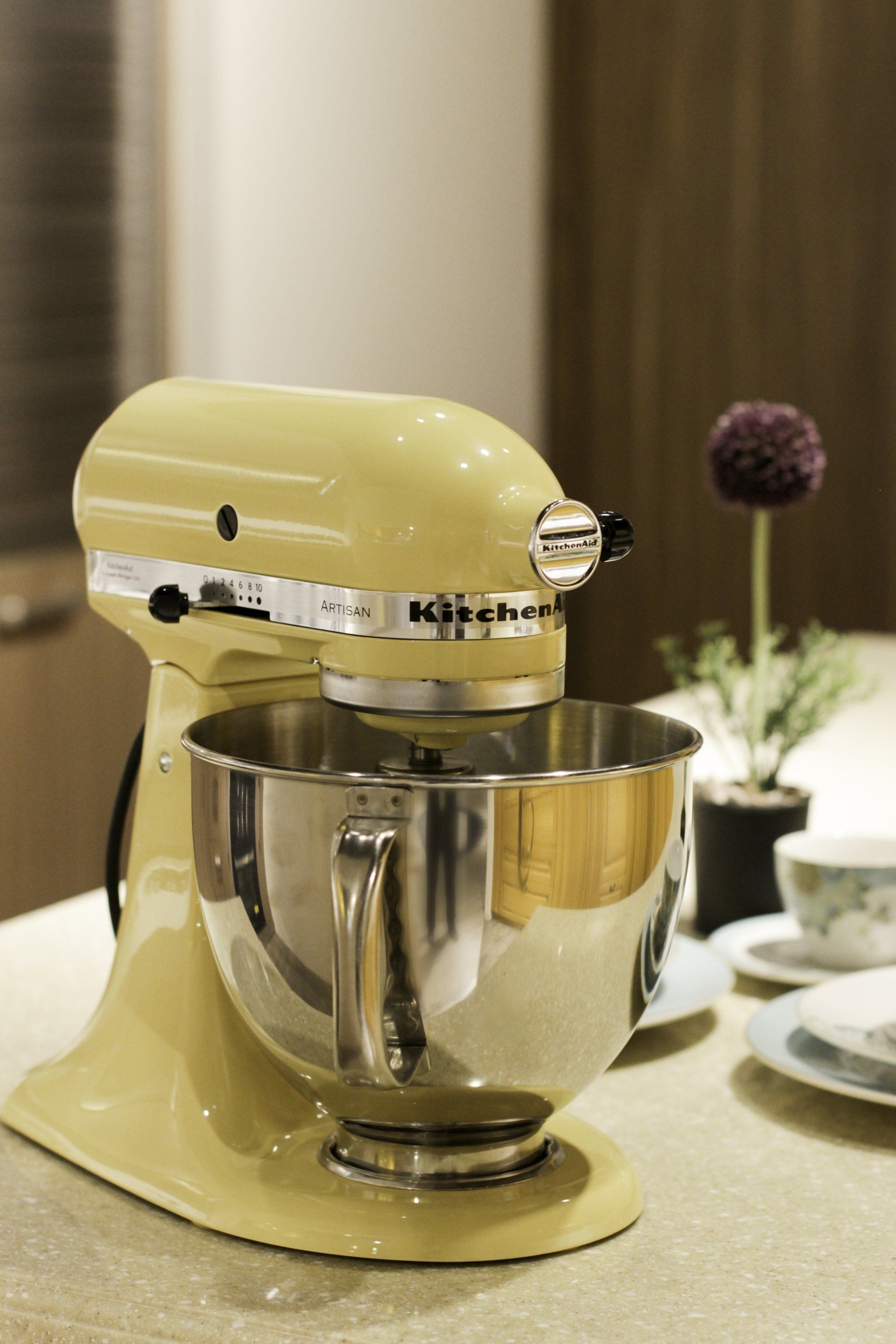 Yellow KitchenAid mixer with stainless steel bowl on a countertop.