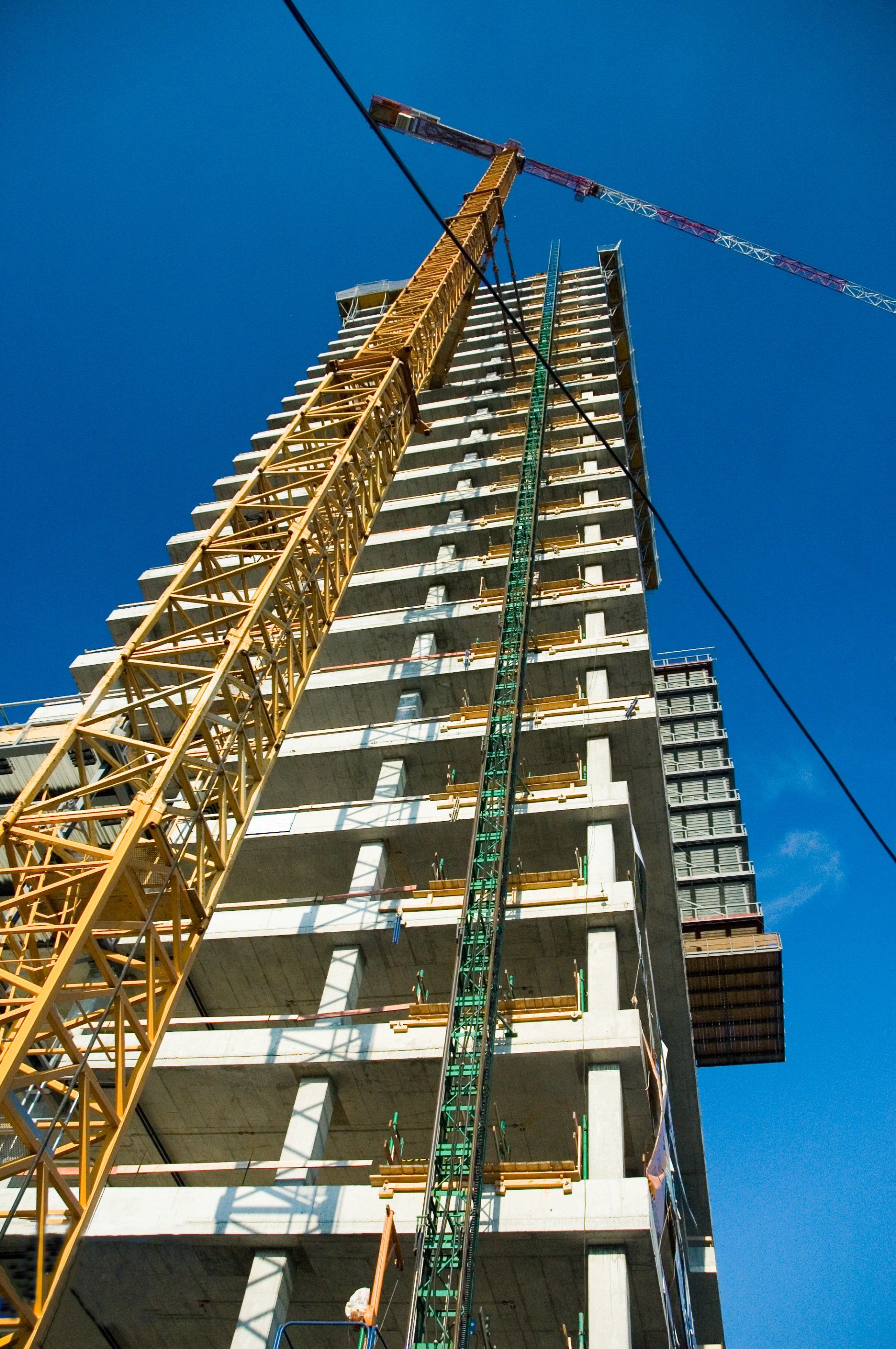 Se está construyendo un edificio alto con una grúa en primer plano. Puntales metalicos para cimra con Puntales Monterrey.