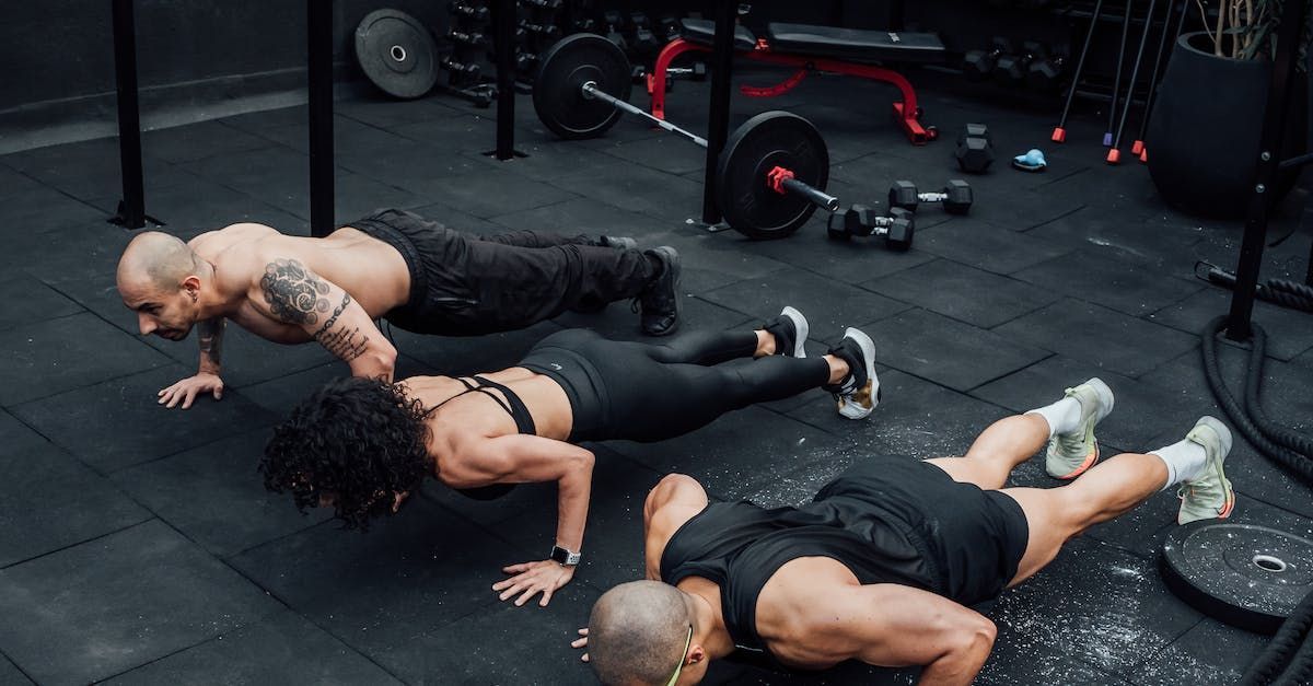 three people are doing push ups in a gym .