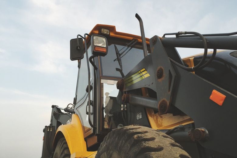 Yellow and black construction loader against a cloudy sky.