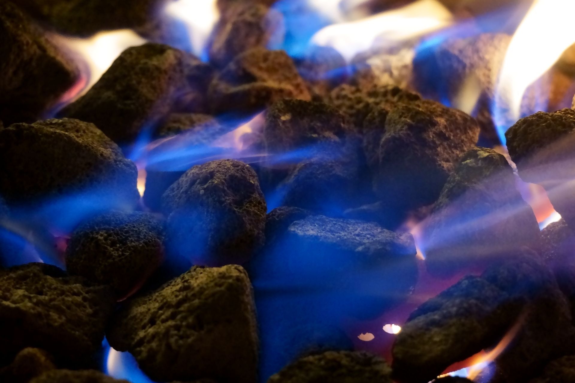A close up of a fire pit with blue flames coming out of the coals.