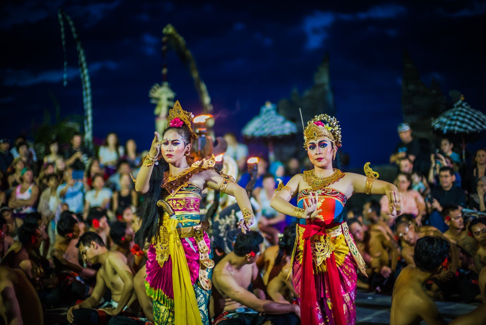 Two women are dancing in front of a crowd of people.