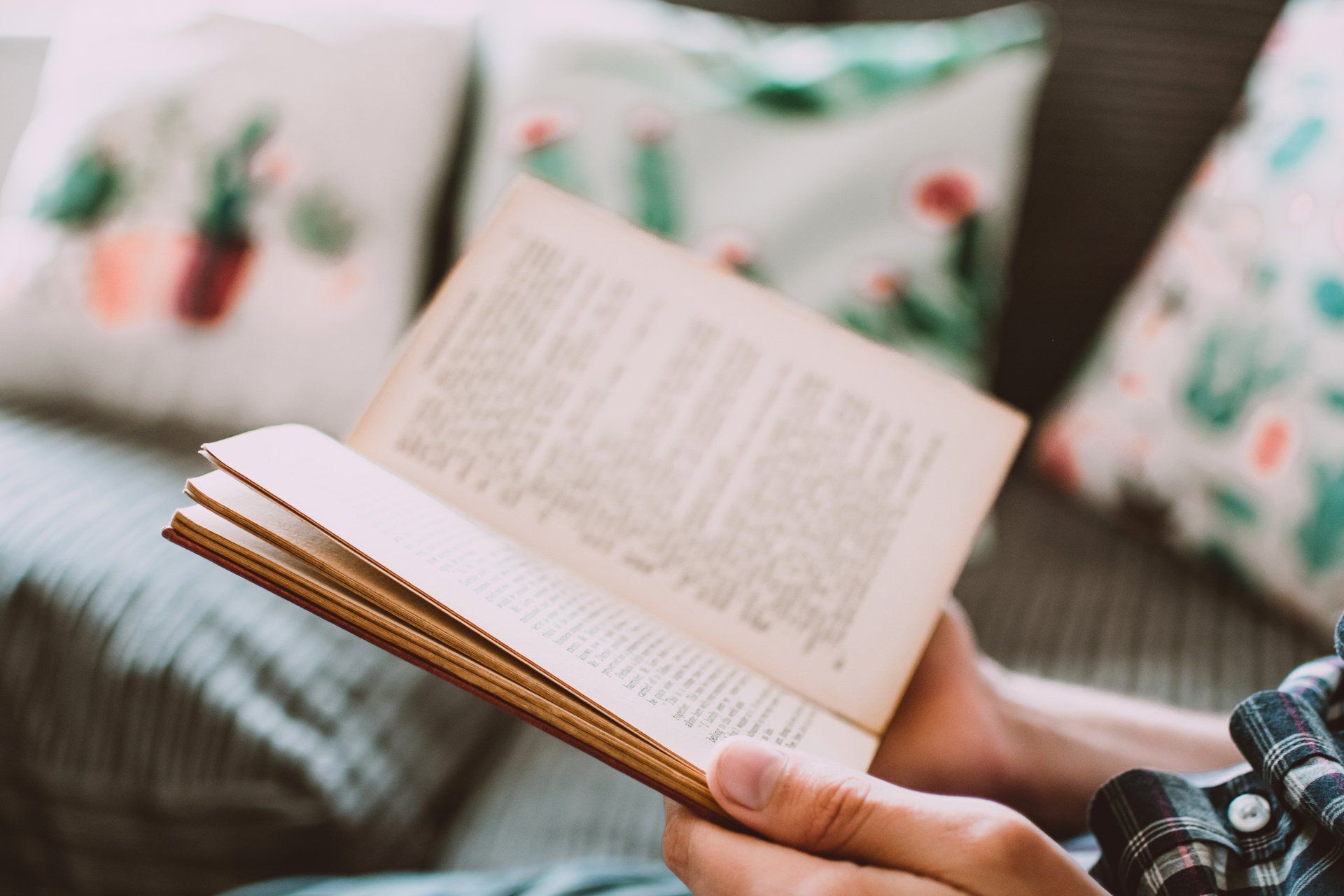 A person is sitting on a couch reading a book.