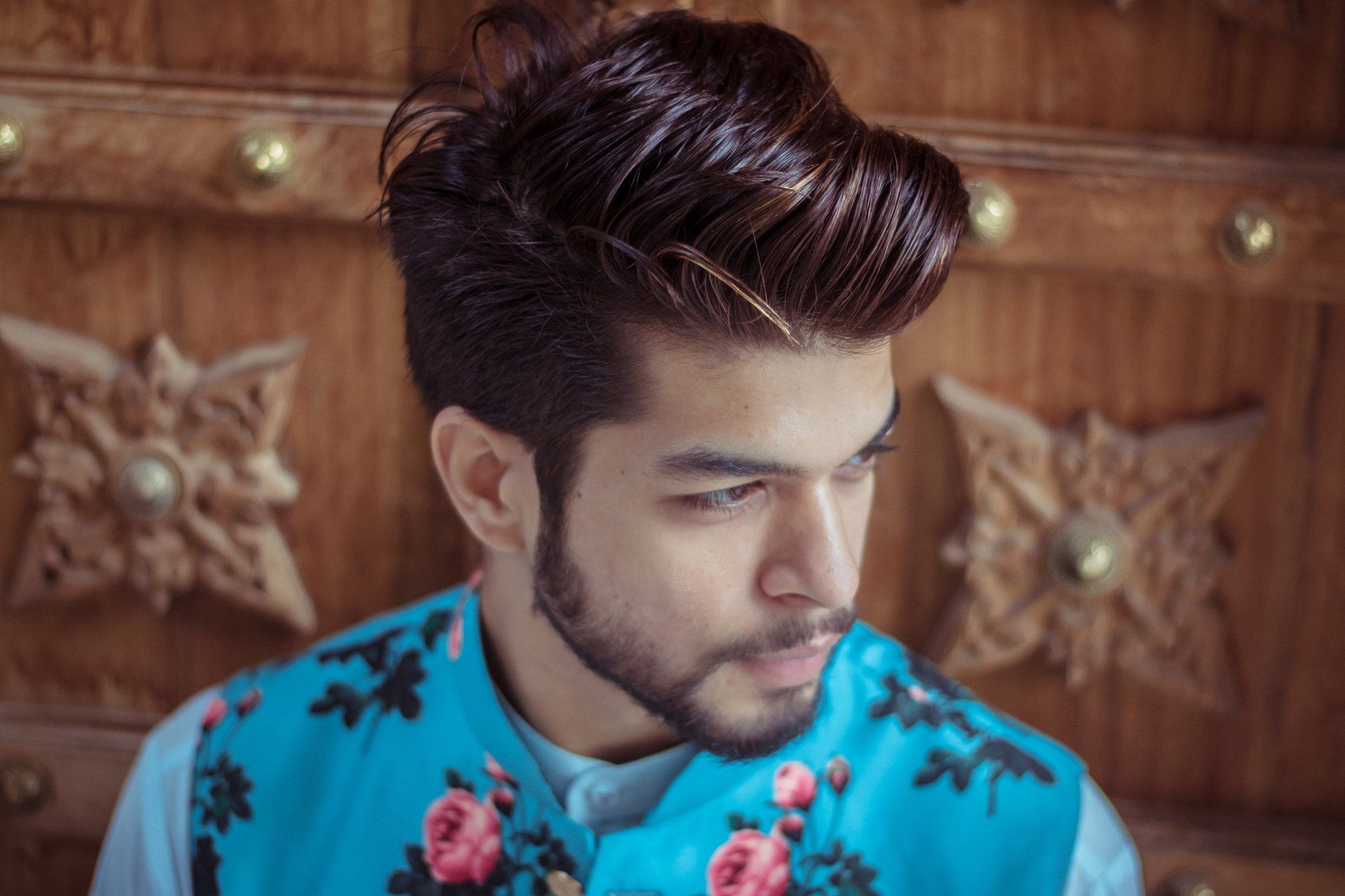 a man with a beard is wearing a blue vest with flowers on it .