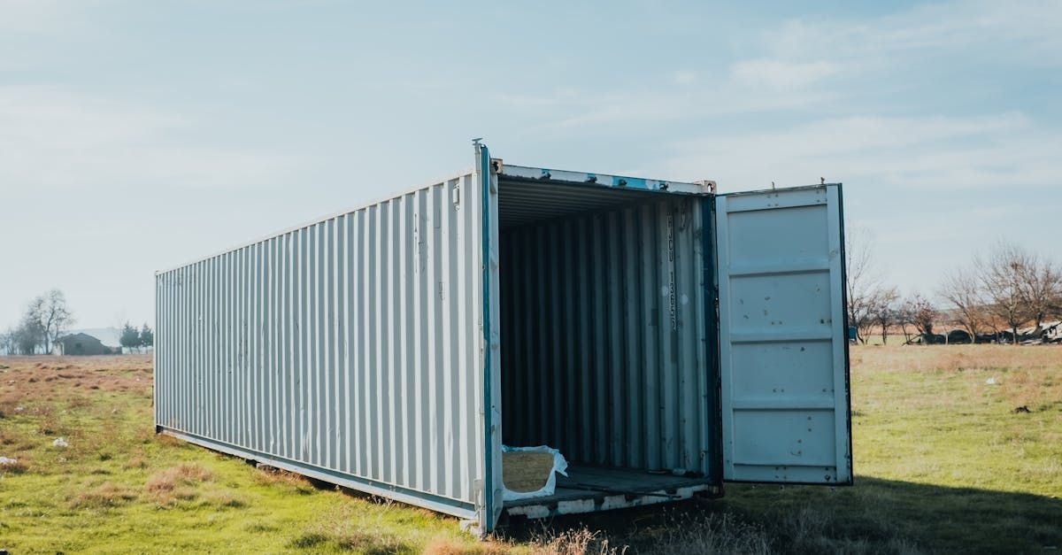 A shipping container is sitting in a grassy field with its door open.