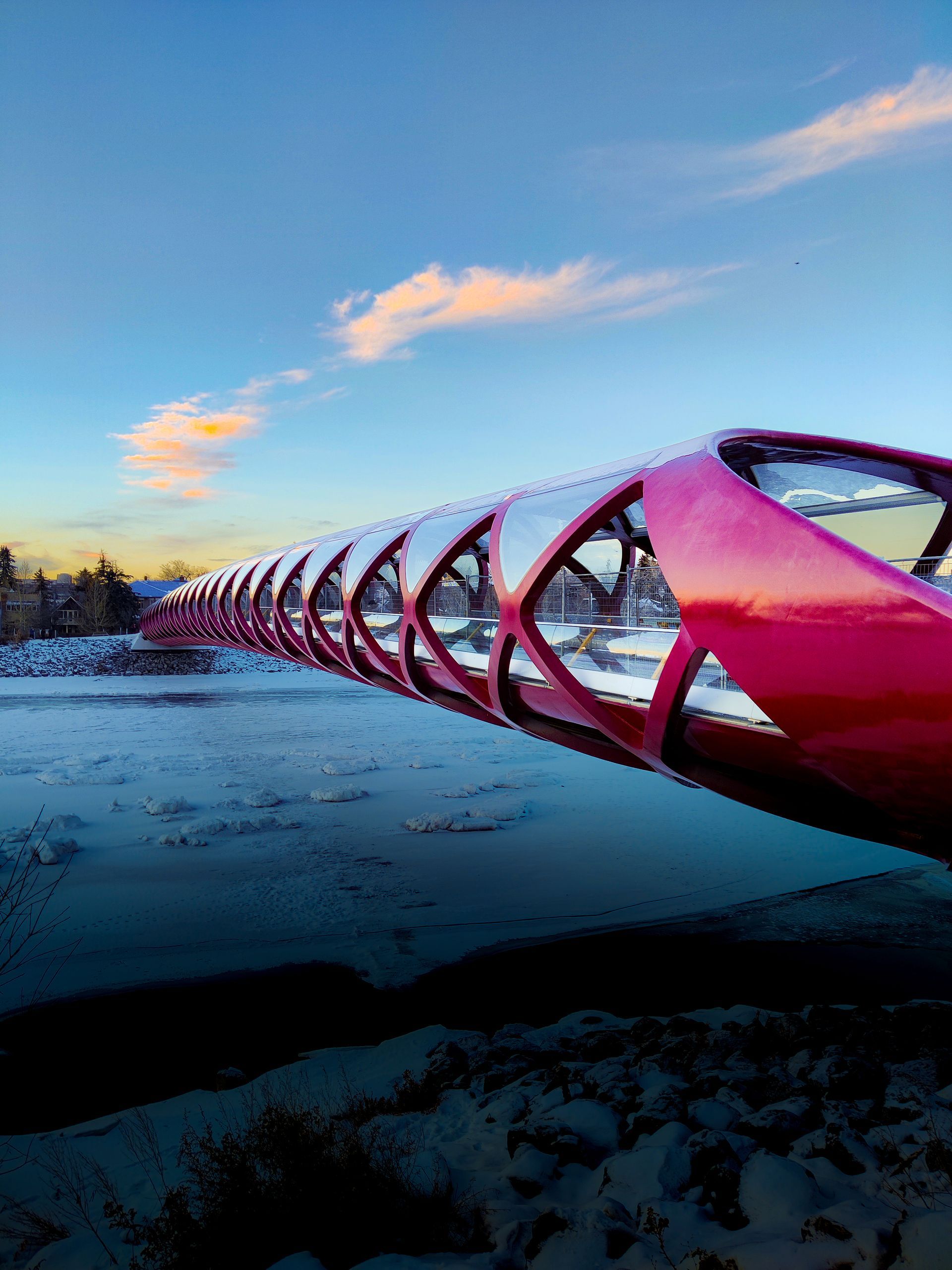 A red bridge over a body of water with a blue sky in the background.