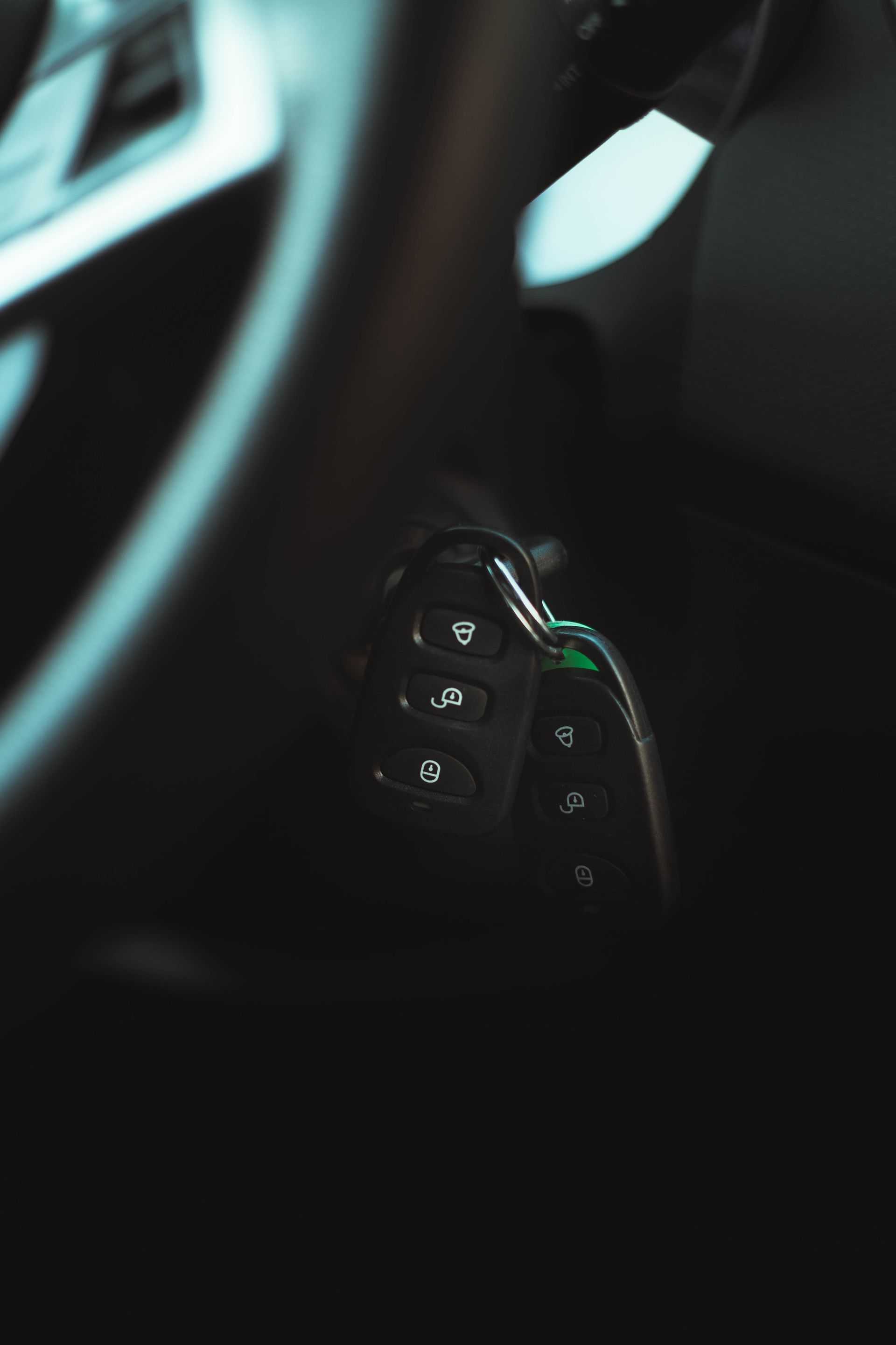Steering wheel detail with control buttons in a car interior; dark, with some silver accents.