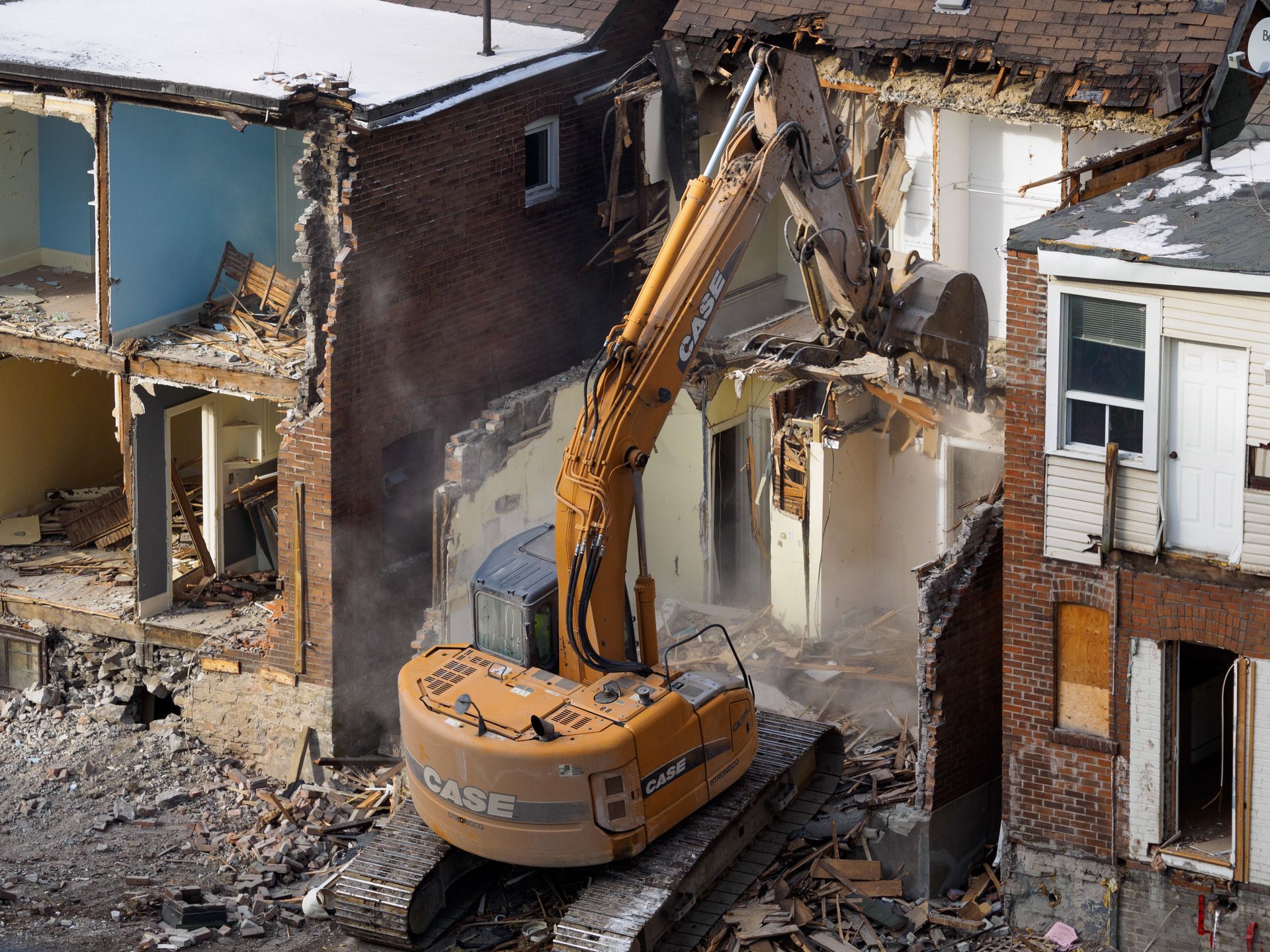 A case excavator is demolishing a brick building