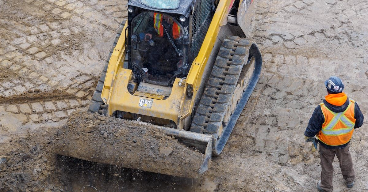 A man is standing in front of a bulldozer moving dirt on a construction site.