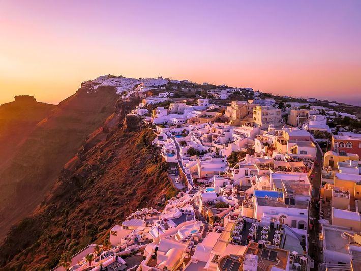 An aerial view of a small town on top of a hill at sunset.