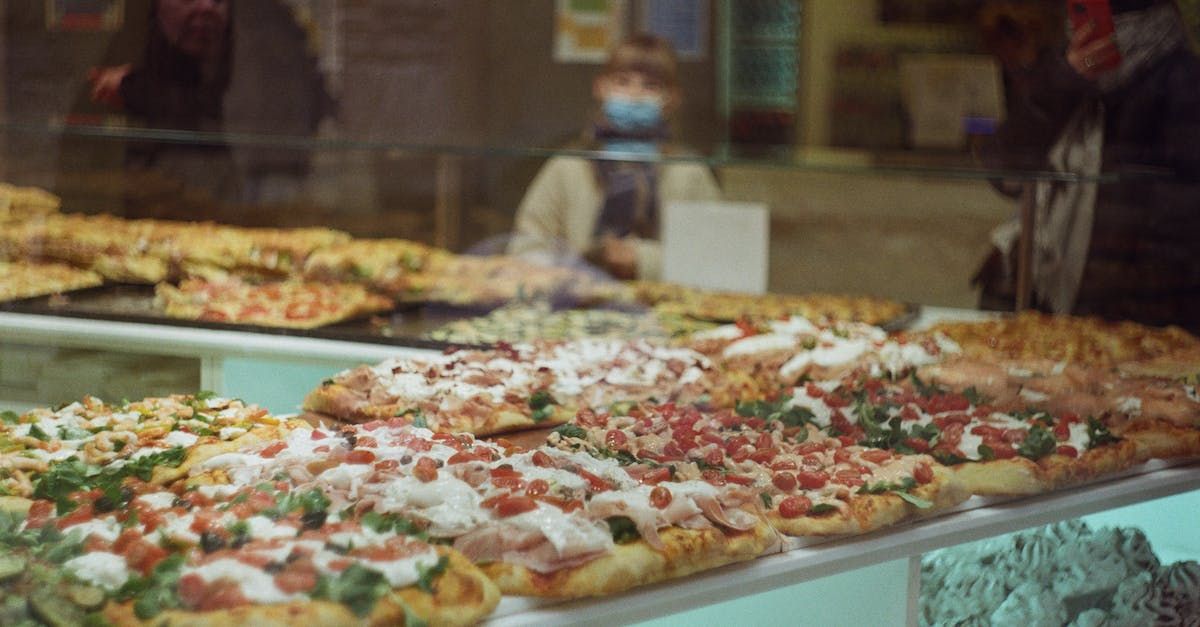 Italian bakery that has a table of different types of freshly baked focaccia breads with different toppings.