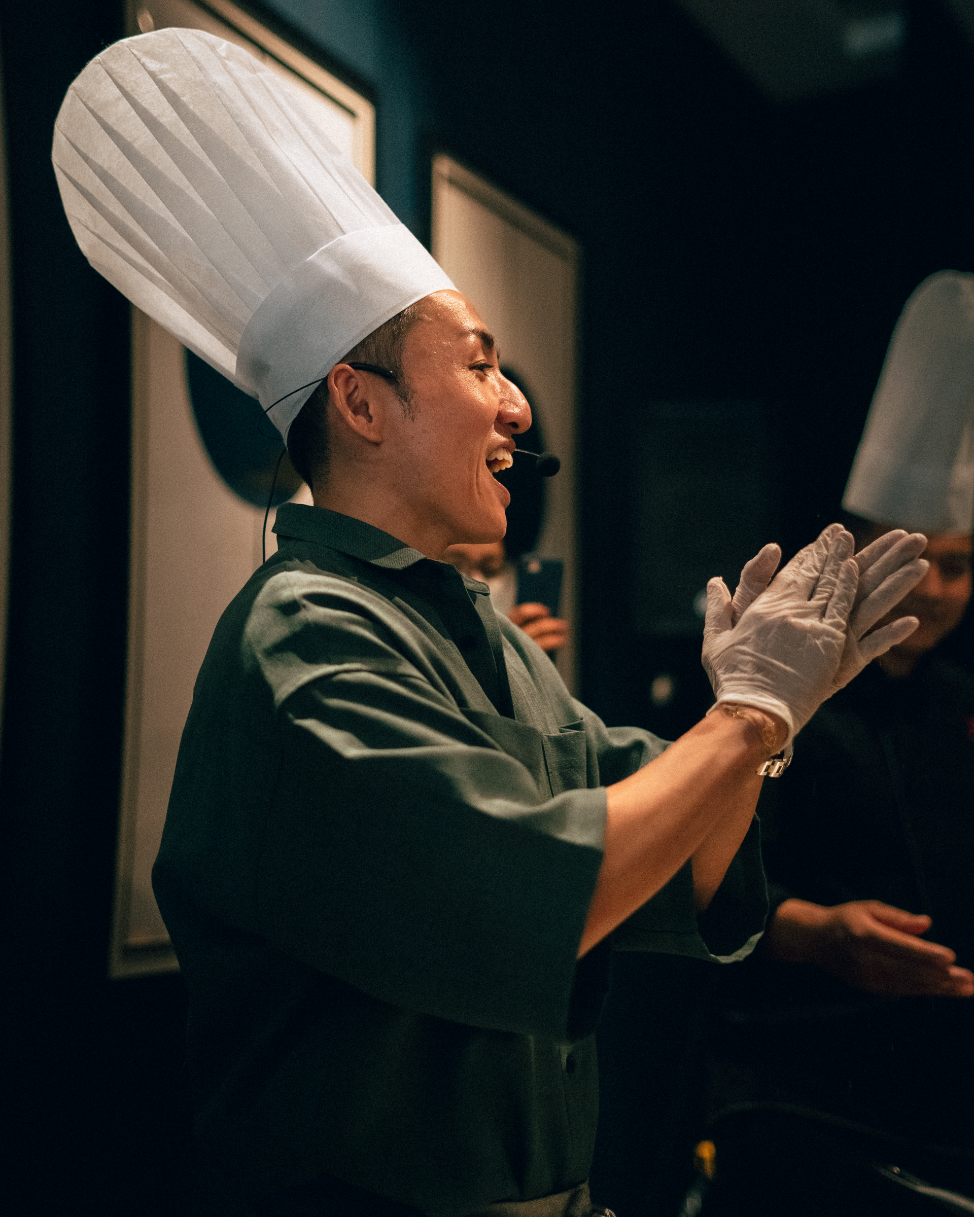 A man wearing a chef 's hat and gloves is clapping his hands.