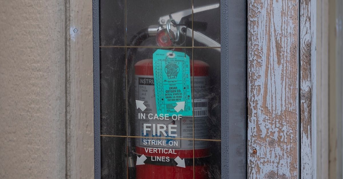 A fire extinguisher is sitting in a glass case on the side of a building.
