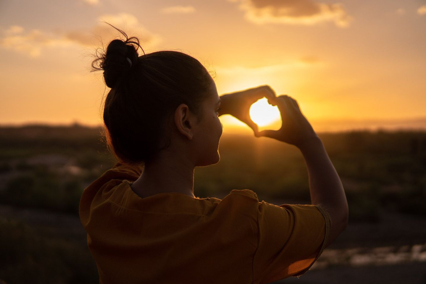 Sunrise and hands making a heart symbol