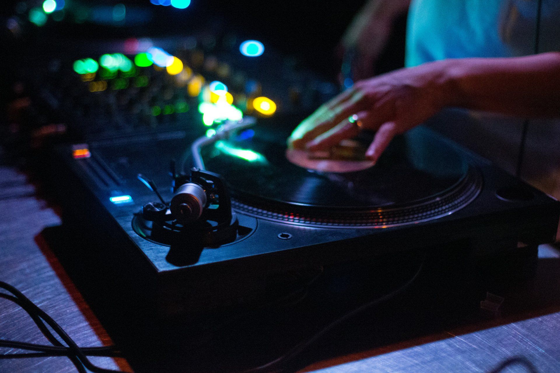 A person is playing a record on a turntable in a dark room.