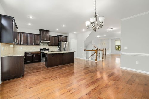 A kitchen and dining room in a house with hardwood floors and a chandelier.