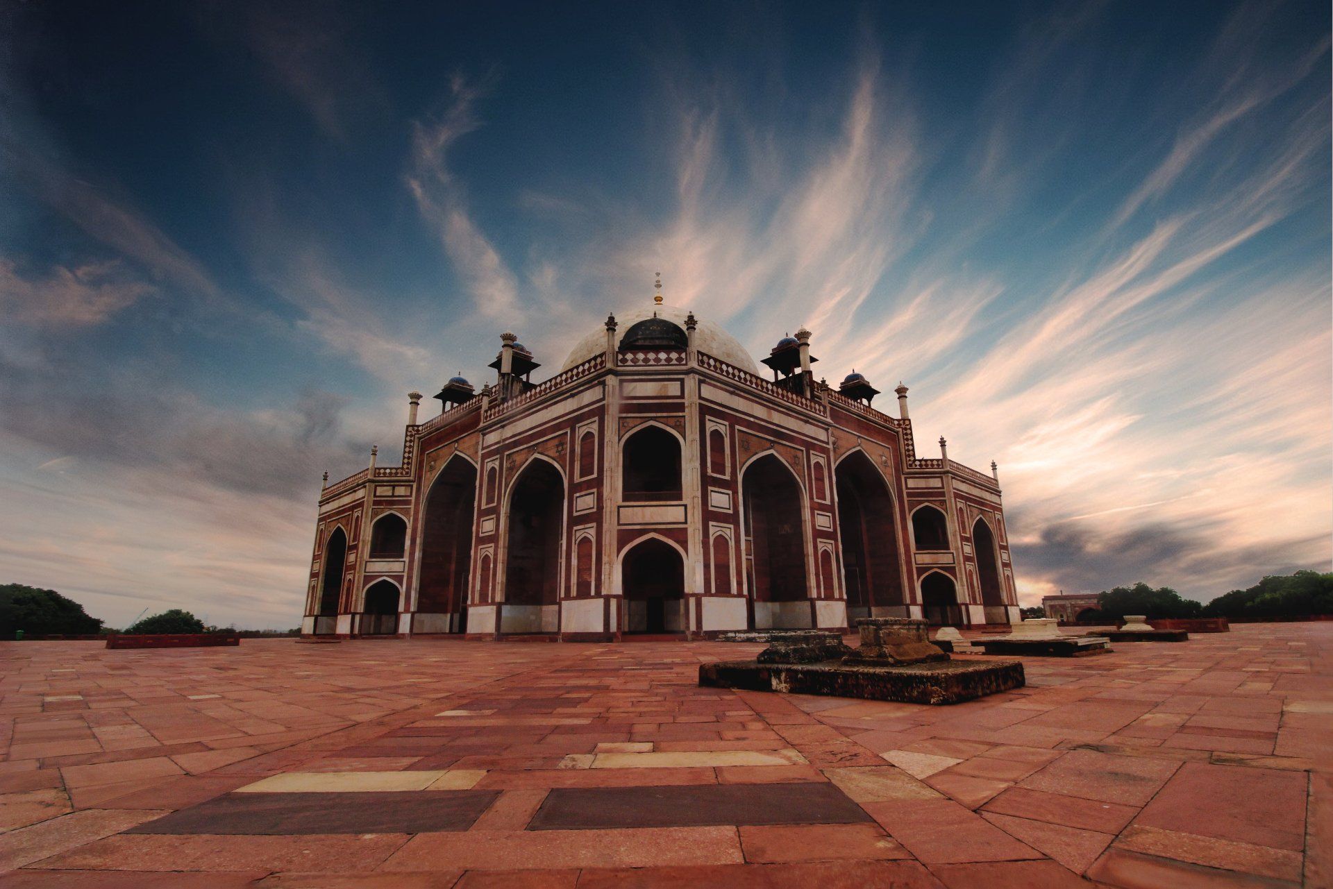 Humayun's Tomb, Delhi, India, red sandstone and white marble Mughal architecture under a dramatic, cloudy sky.