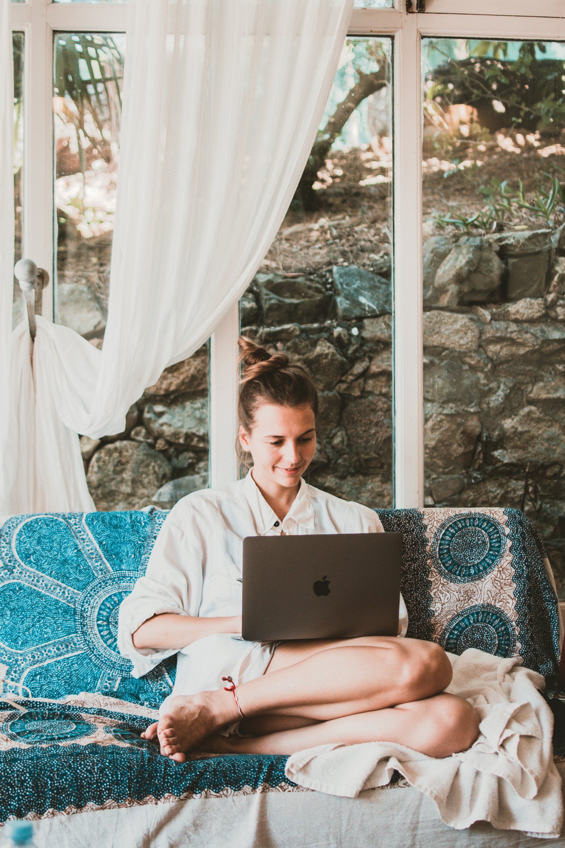 Une femme est assise sur un canapé et utilise un ordinateur portable.