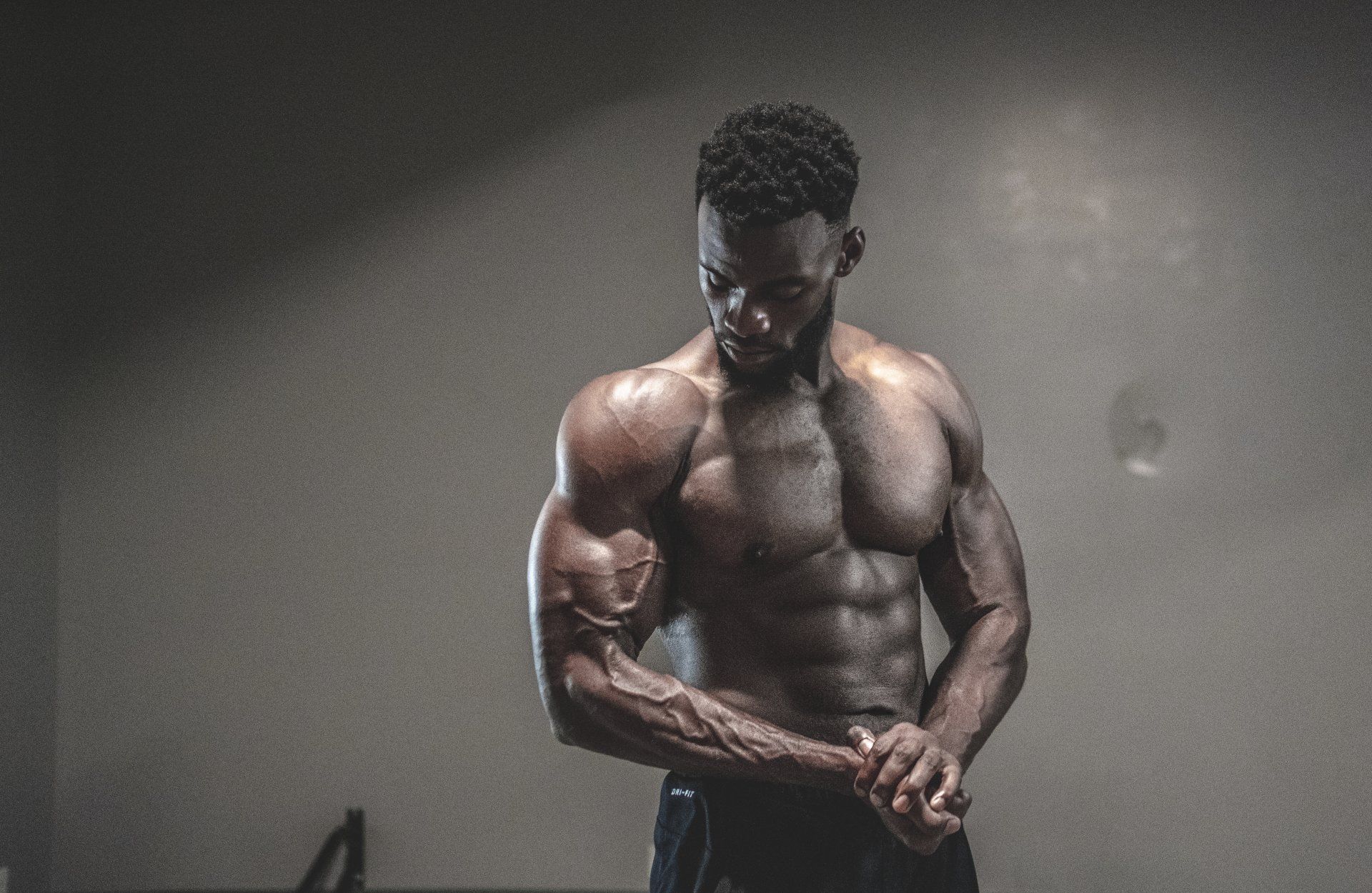 A shirtless man is flexing his muscles in a gym.