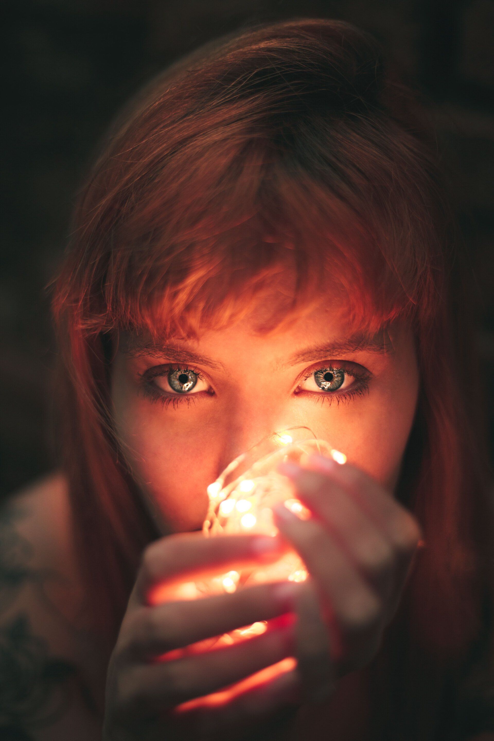 A woman is holding a light bulb in front of her face.