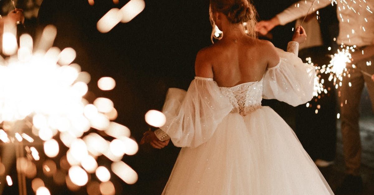 A woman in a wedding dress is holding sparklers in her hands.