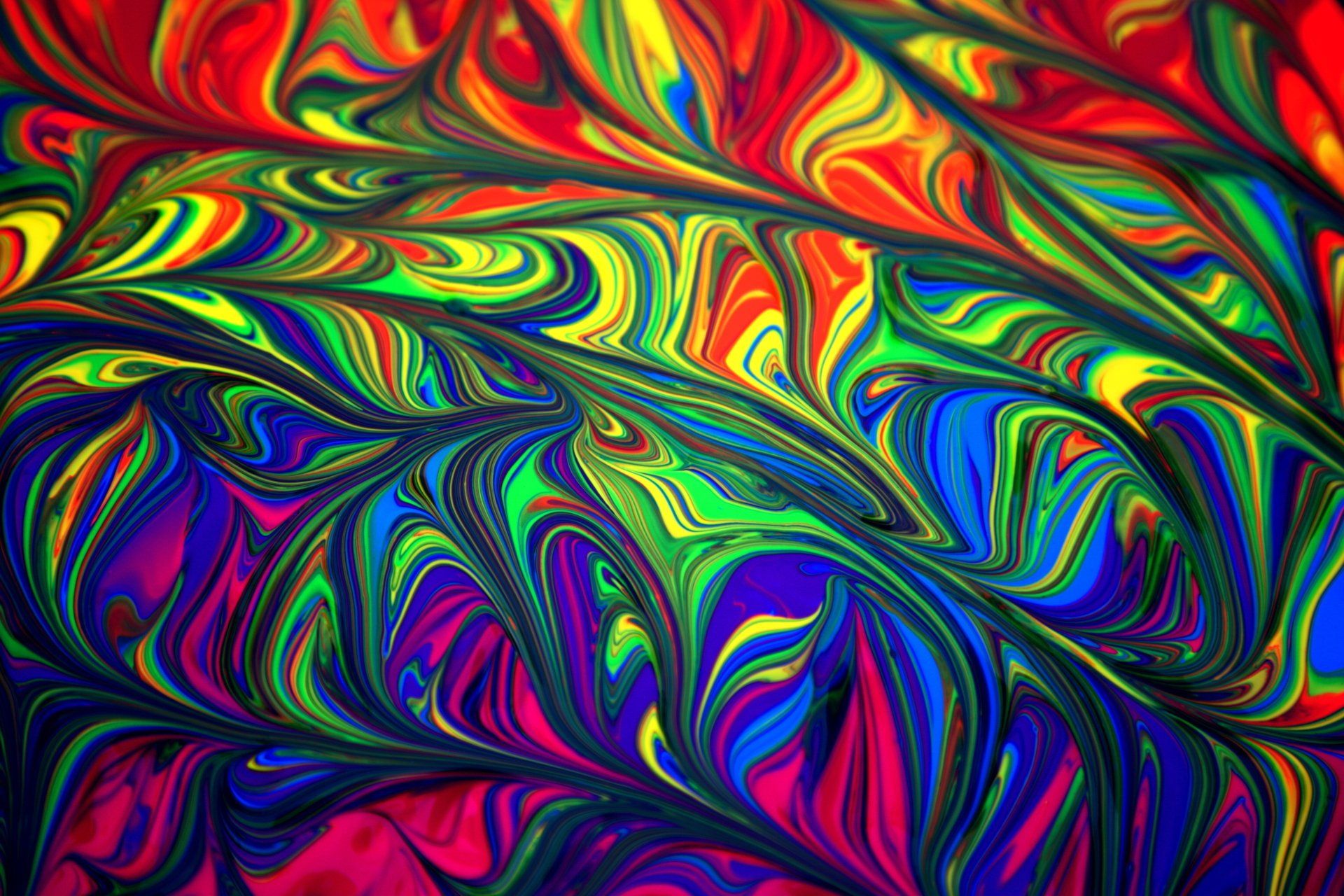Swirled, vibrant paint in rainbow hues: red, blue, green, yellow, and purple creating a psychedelic pattern.
