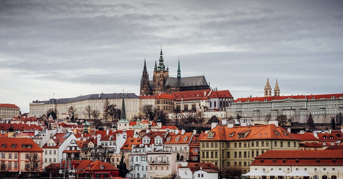 Panoramatický výhled na pražské Staré Město s červenou střechou, Pražským hradem a katedrálou za zamračeného dne