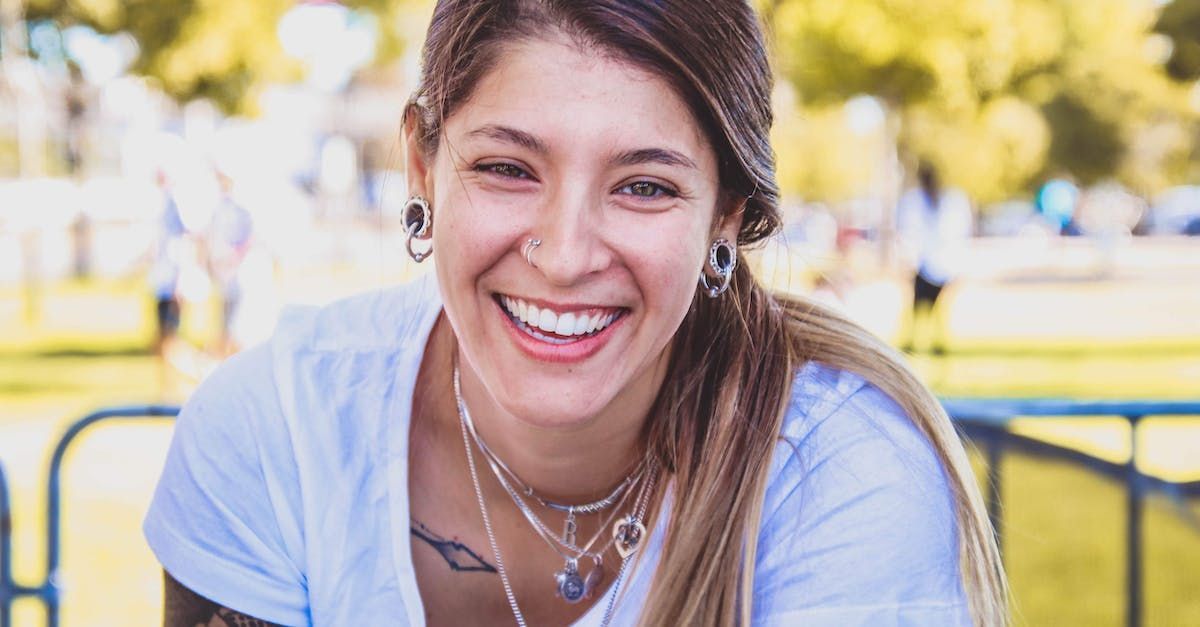 A woman wearing a white shirt and a necklace is smiling.