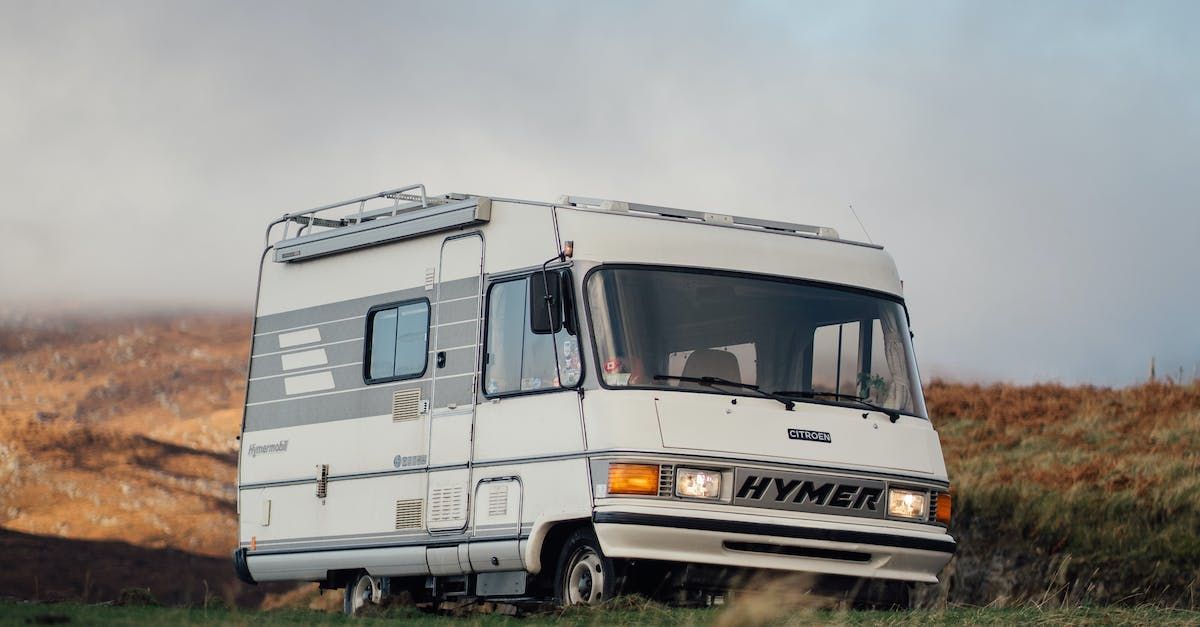 A white rv is parked in a grassy field.