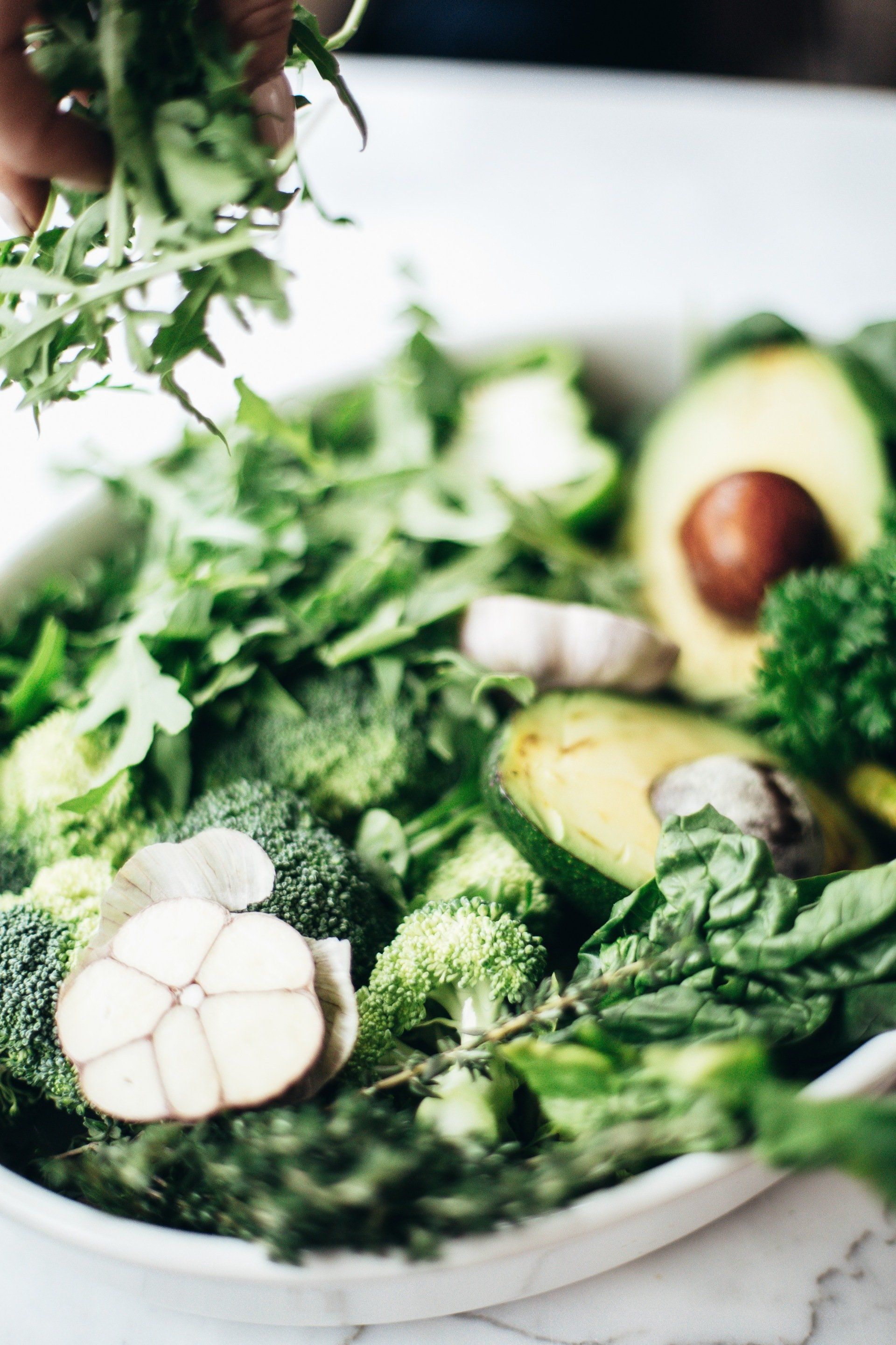 Green salad bowl with broccoli, avocado, herbs, and garlic.