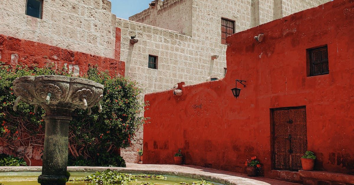 there is a fountain in the middle of a courtyard between two buildings .
