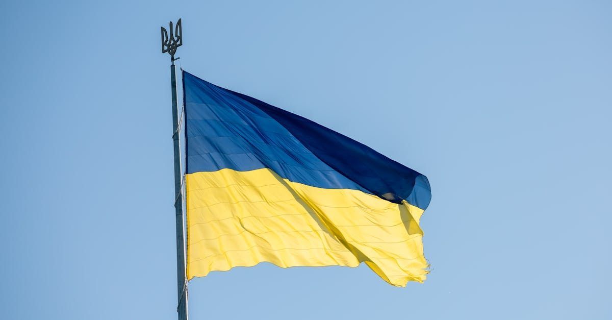 A blue and yellow flag is flying in the wind against a blue sky.