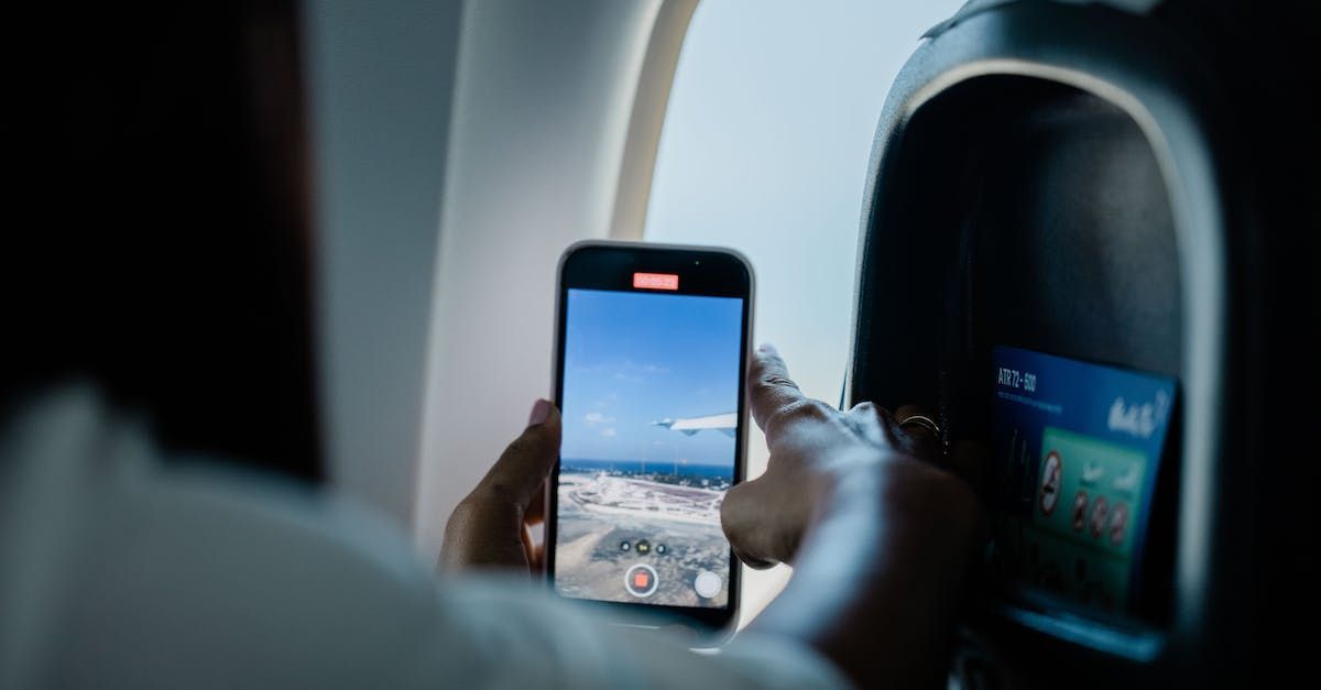 A person is taking a picture of an airplane on a cell phone.