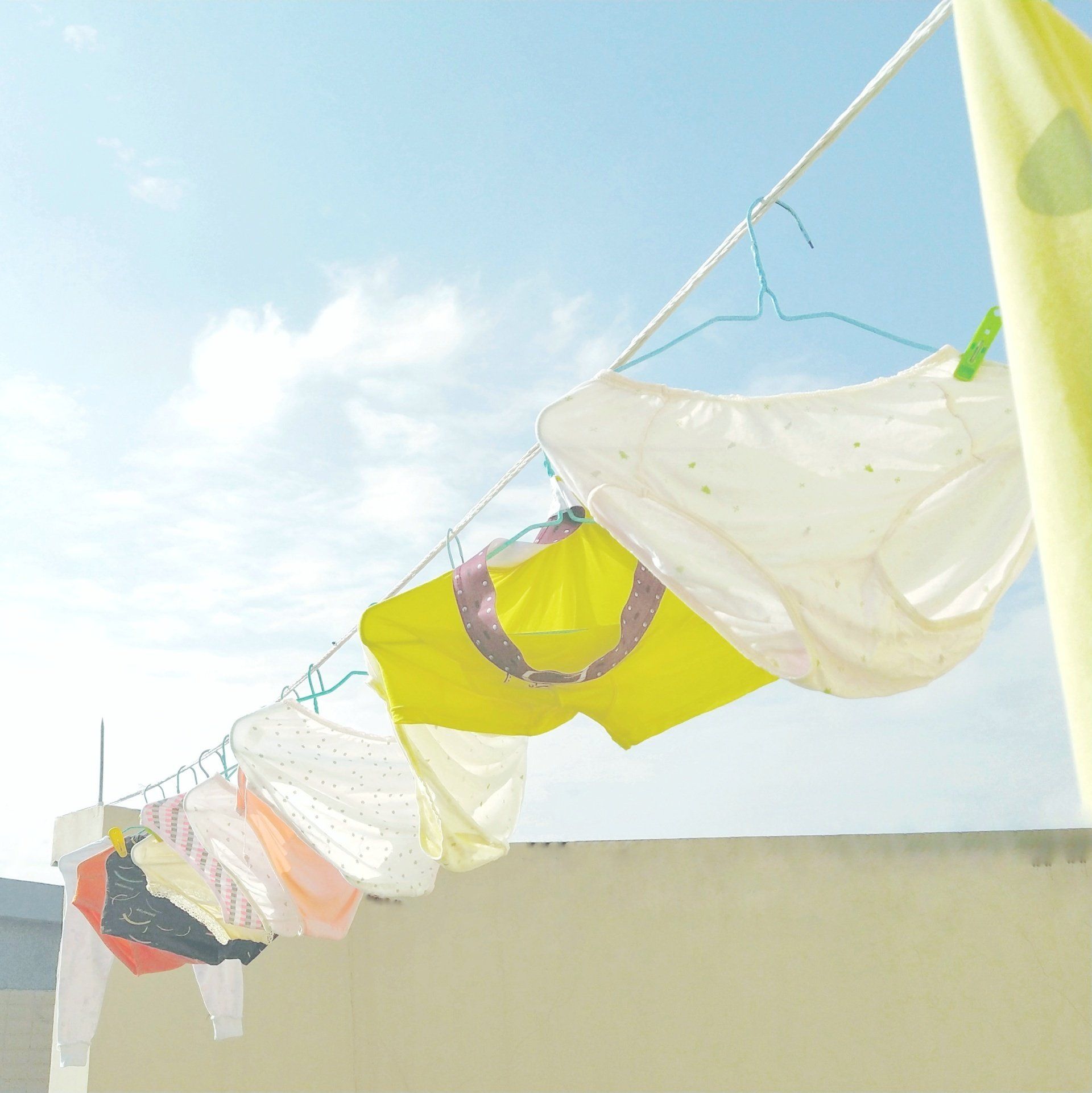 Underwear hanging on a clothesline outdoors under a bright blue sky.