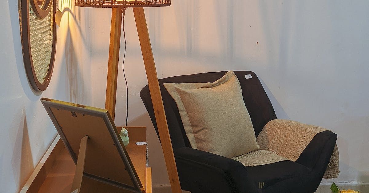 Wooden tripod floor lamp illuminates an armchair with a beige pillow and a woven wall decor.