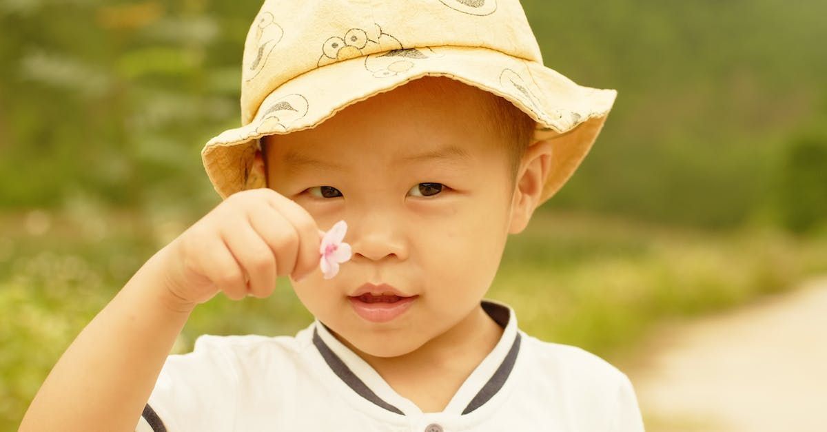 Child examining flower outdoors