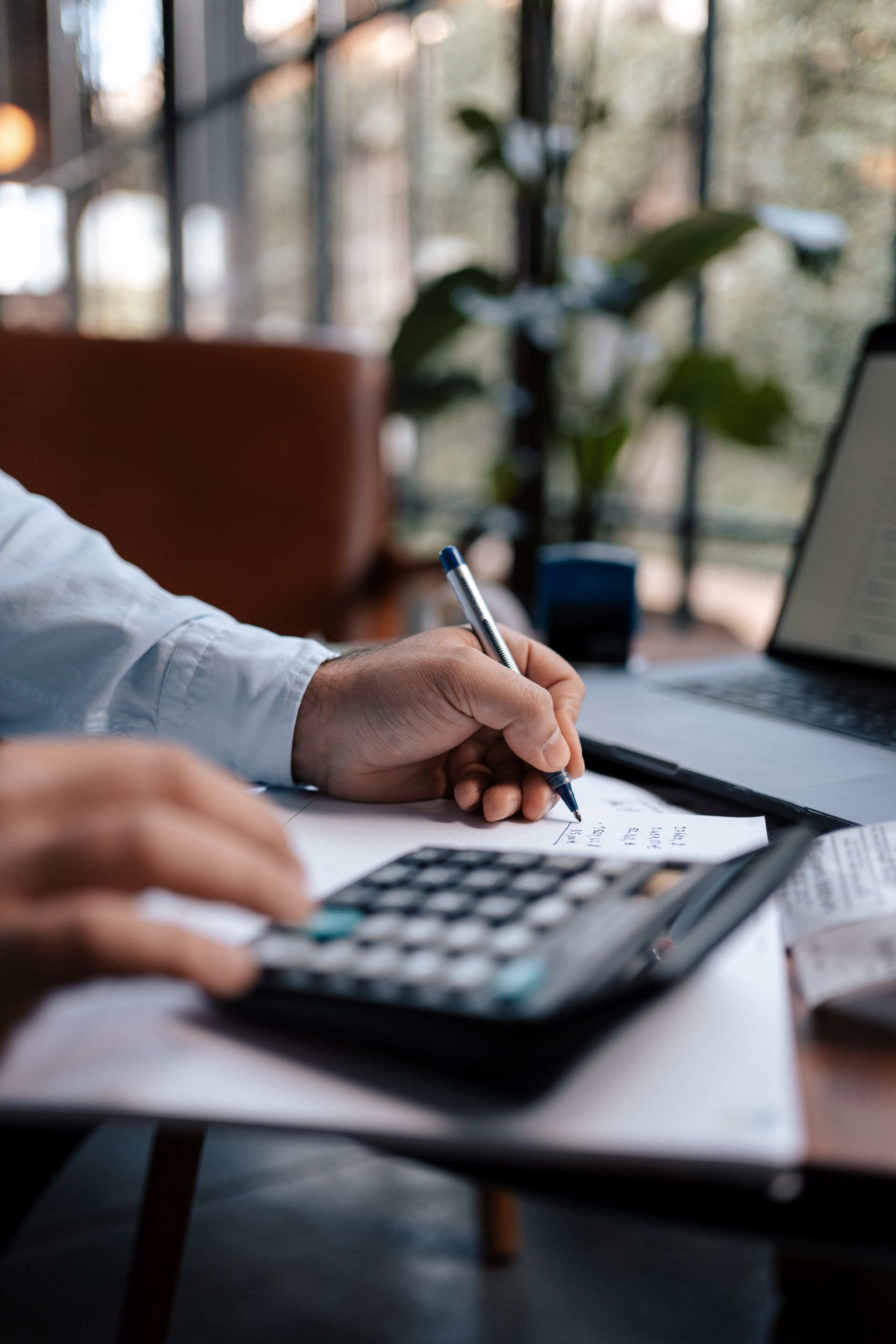 A person is using a calculator and writing on a piece of paper.