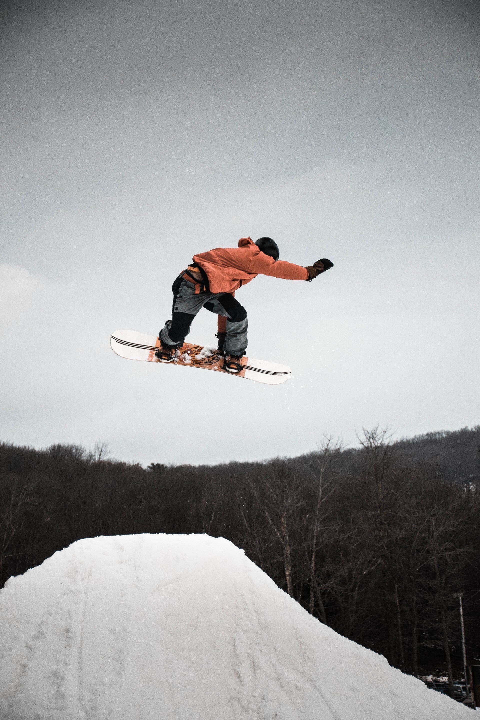 A snowboarder is jumping over a snowy ramp.