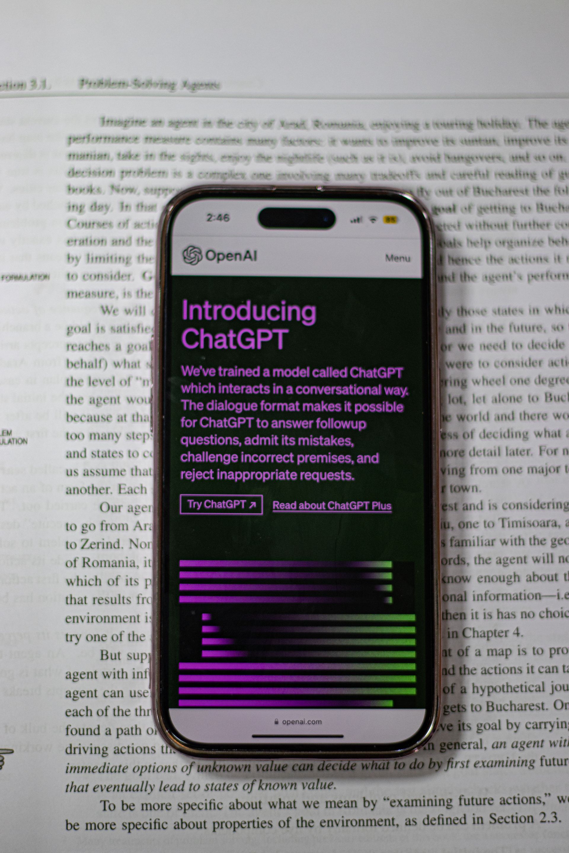 Smartphone displaying the OpenAI ‘Introducing ChatGPT’ webpage placed on top of an open book.