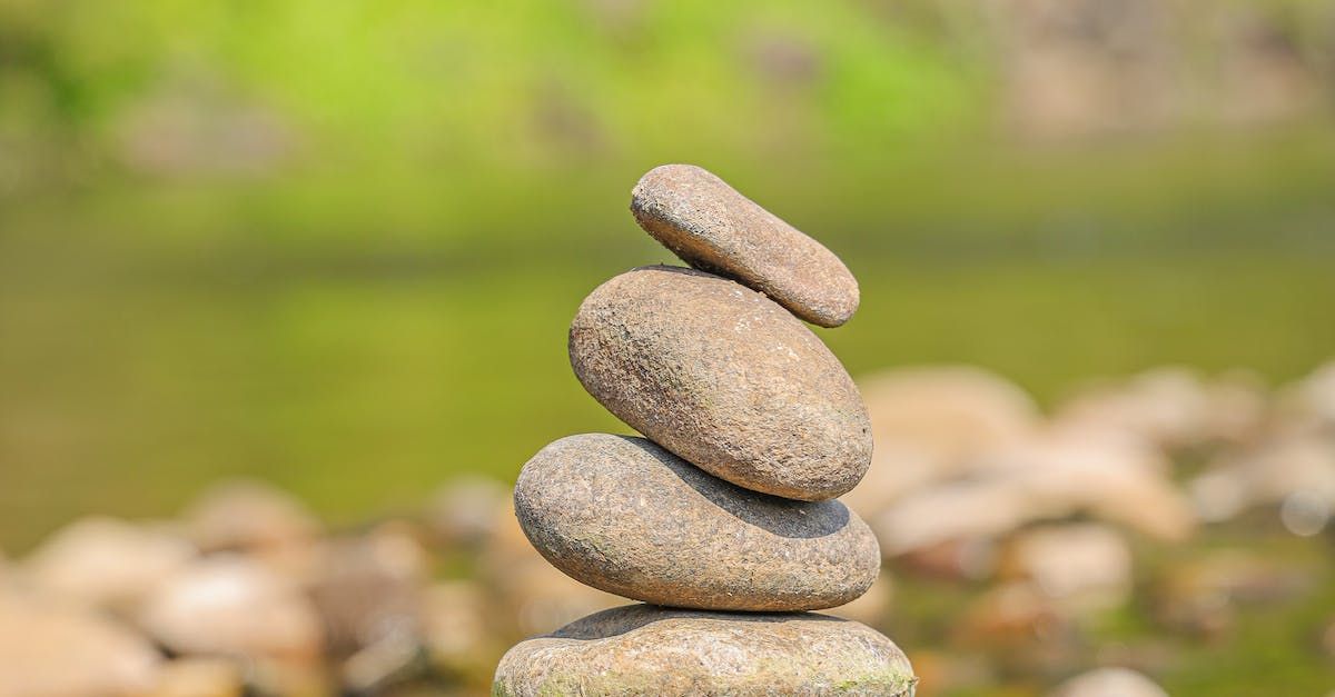 Stack of four grey stones balanced against a blurred green background.
