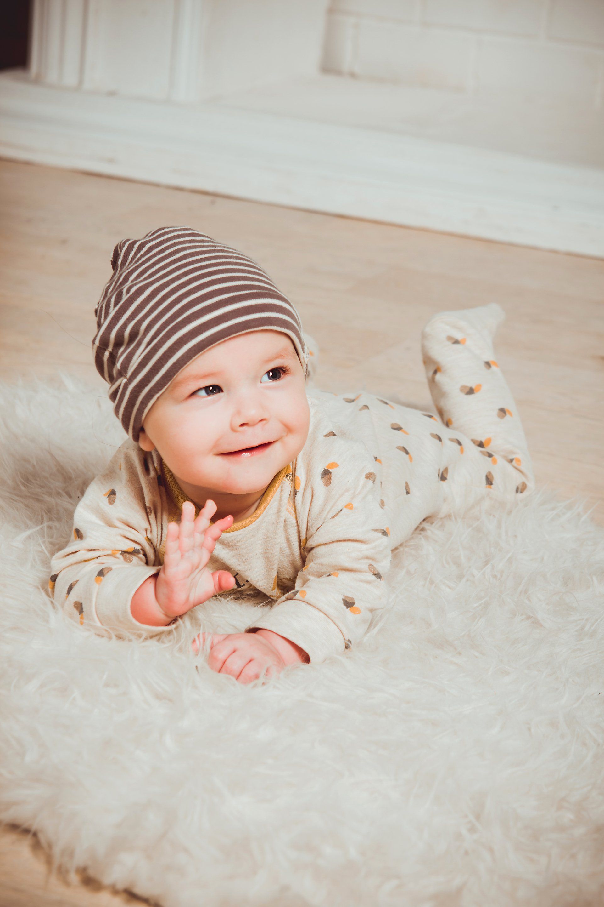 Ein Baby liegt auf dem Bauch auf einer weißen Decke.