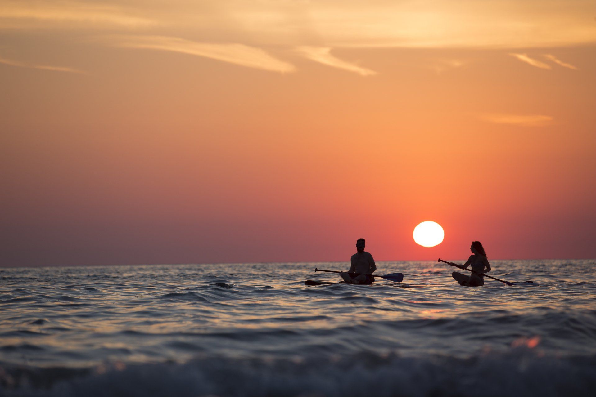 two people sailing in sea with sunset