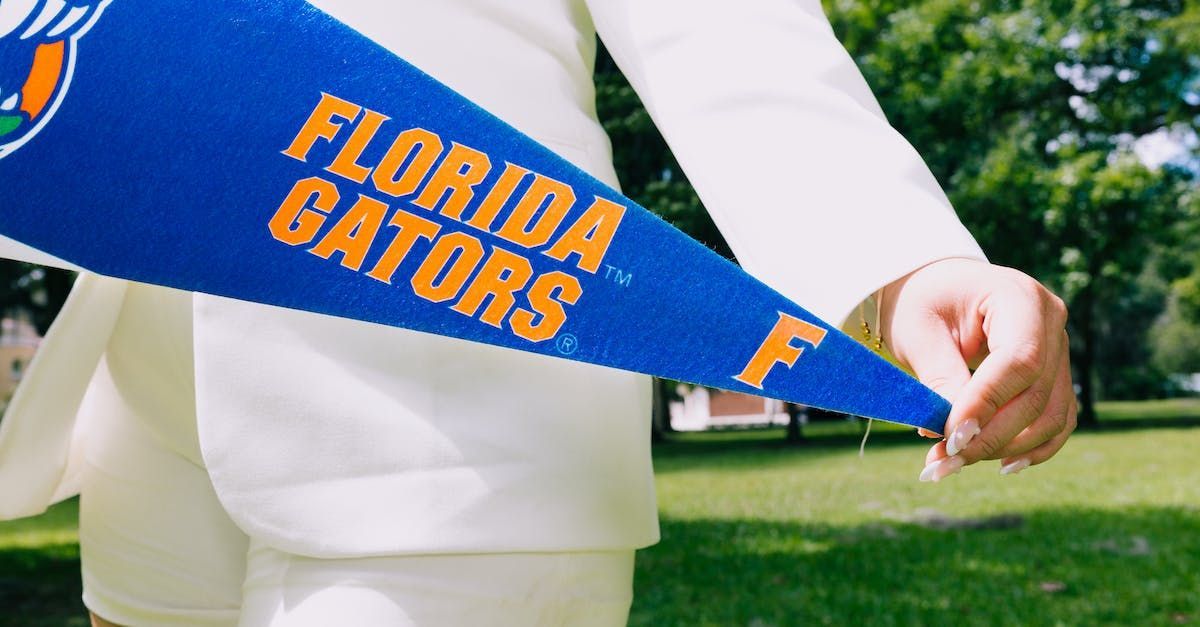 A person in a white suit holding a University of FL flag