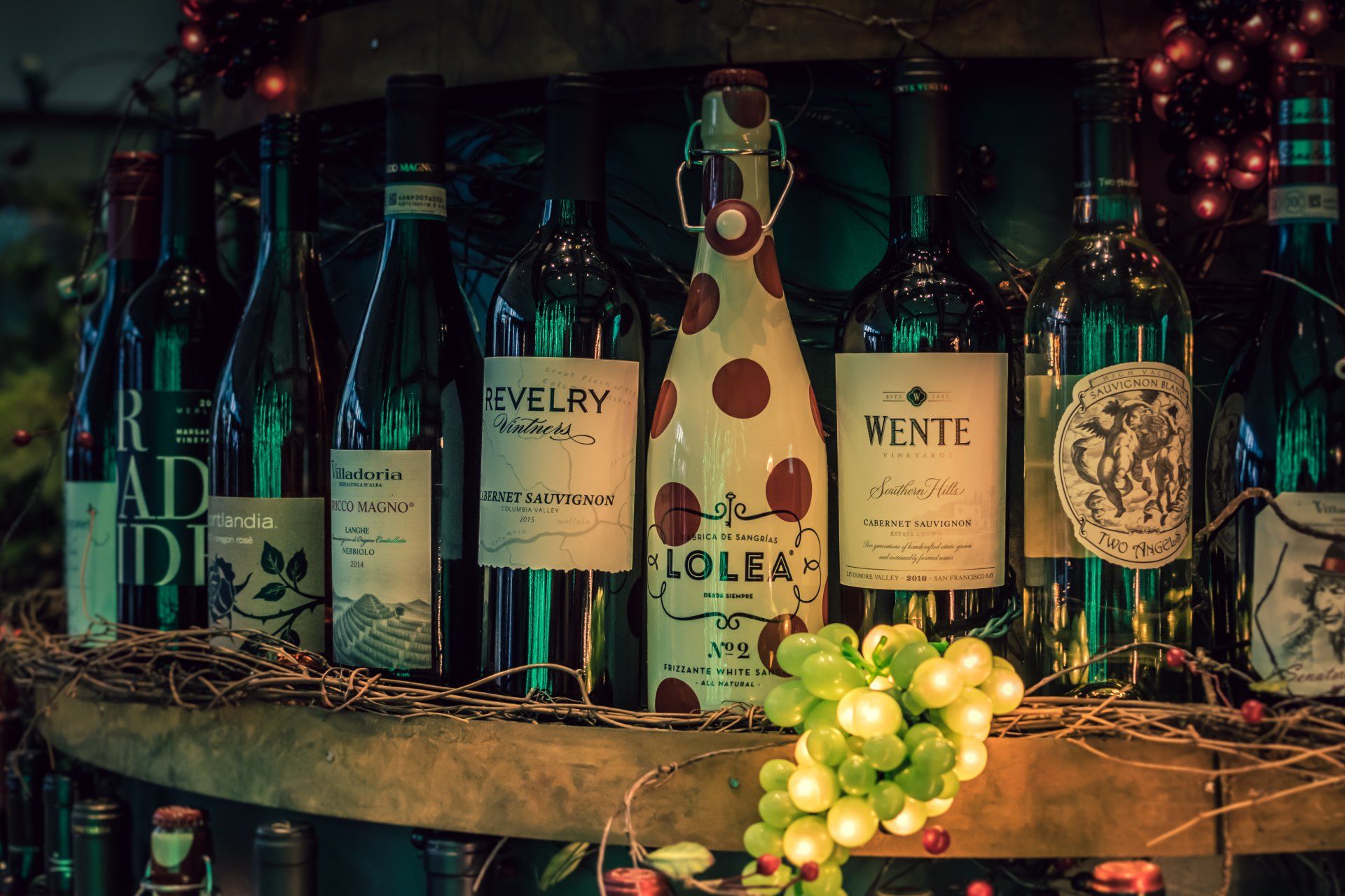 A bunch of bottles of wine are sitting on a wooden shelf.