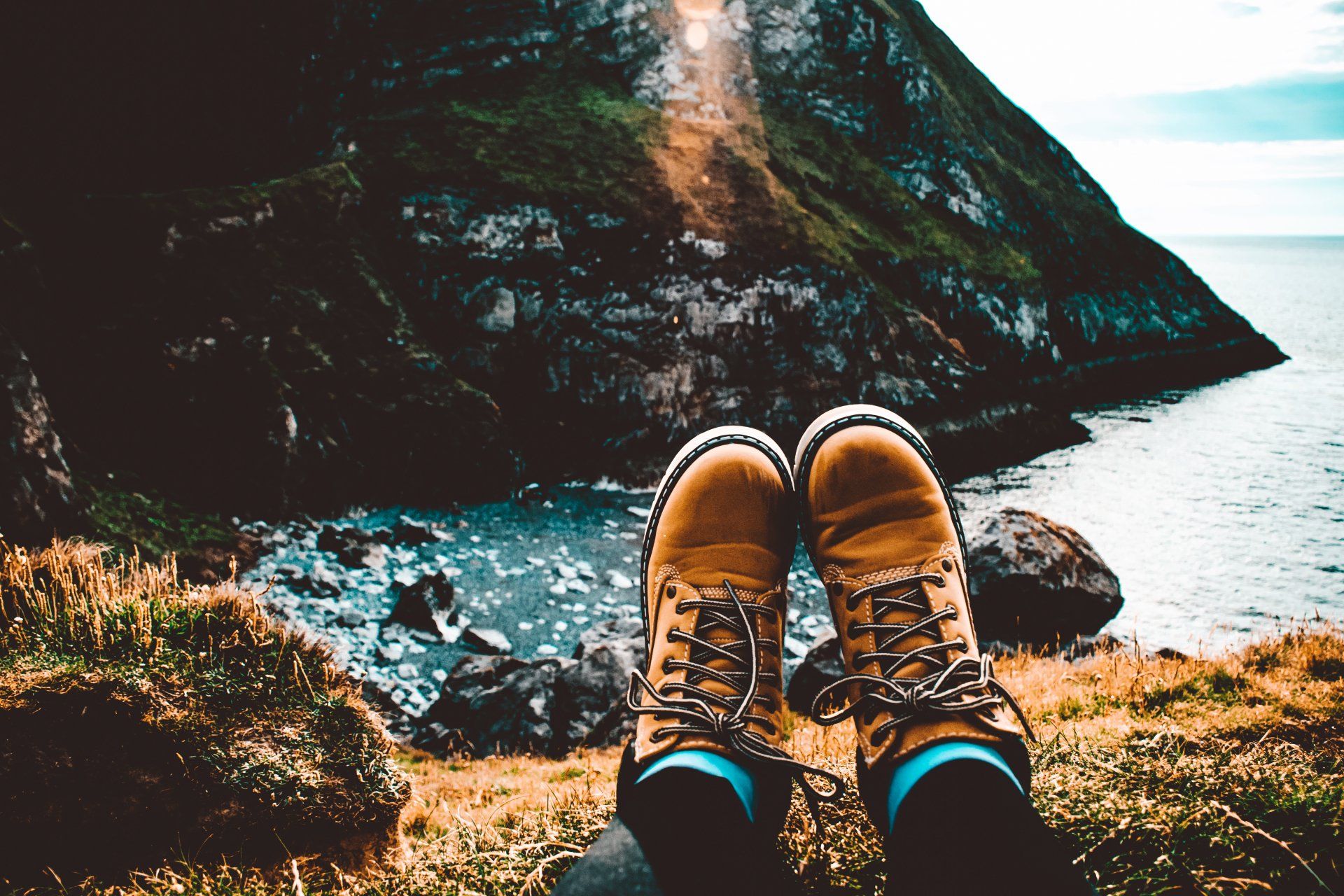 A person 's feet are resting on a rocky cliff overlooking the ocean.