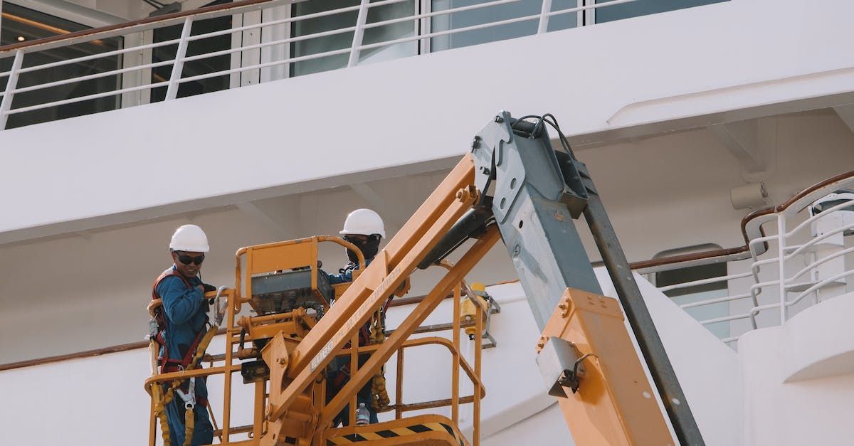 Two men are working on a cruise ship with a crane.
