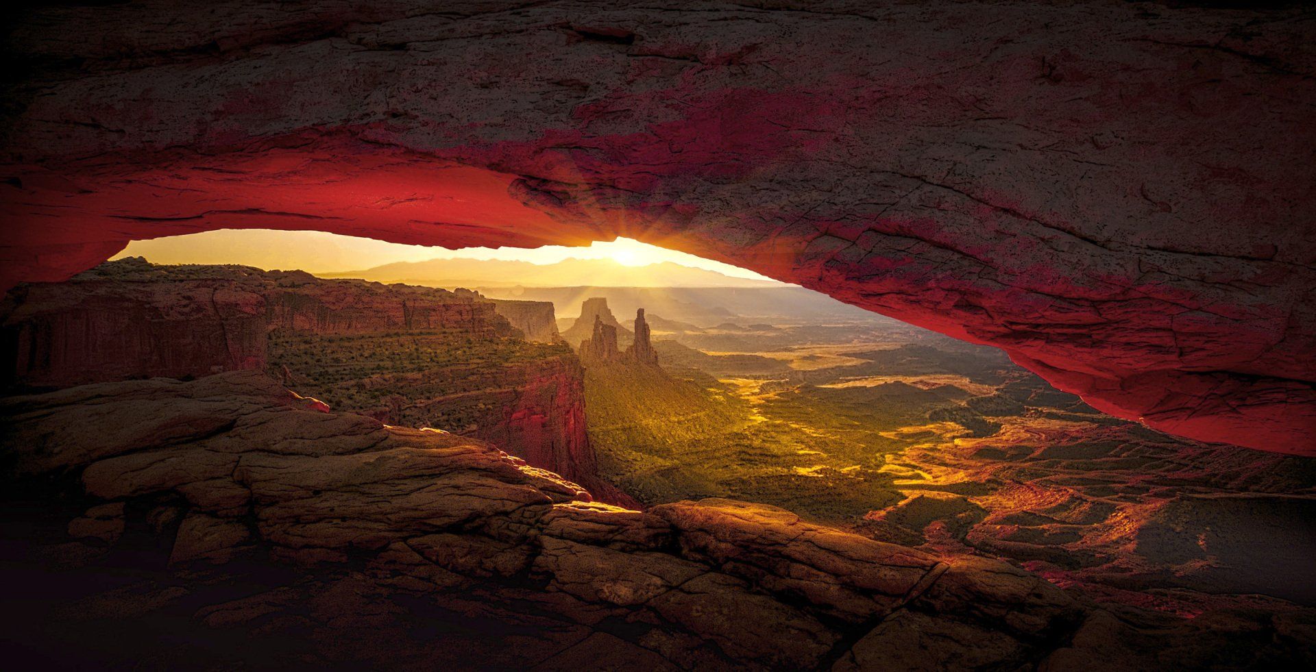 the sun is shining through the archway in the canyon .