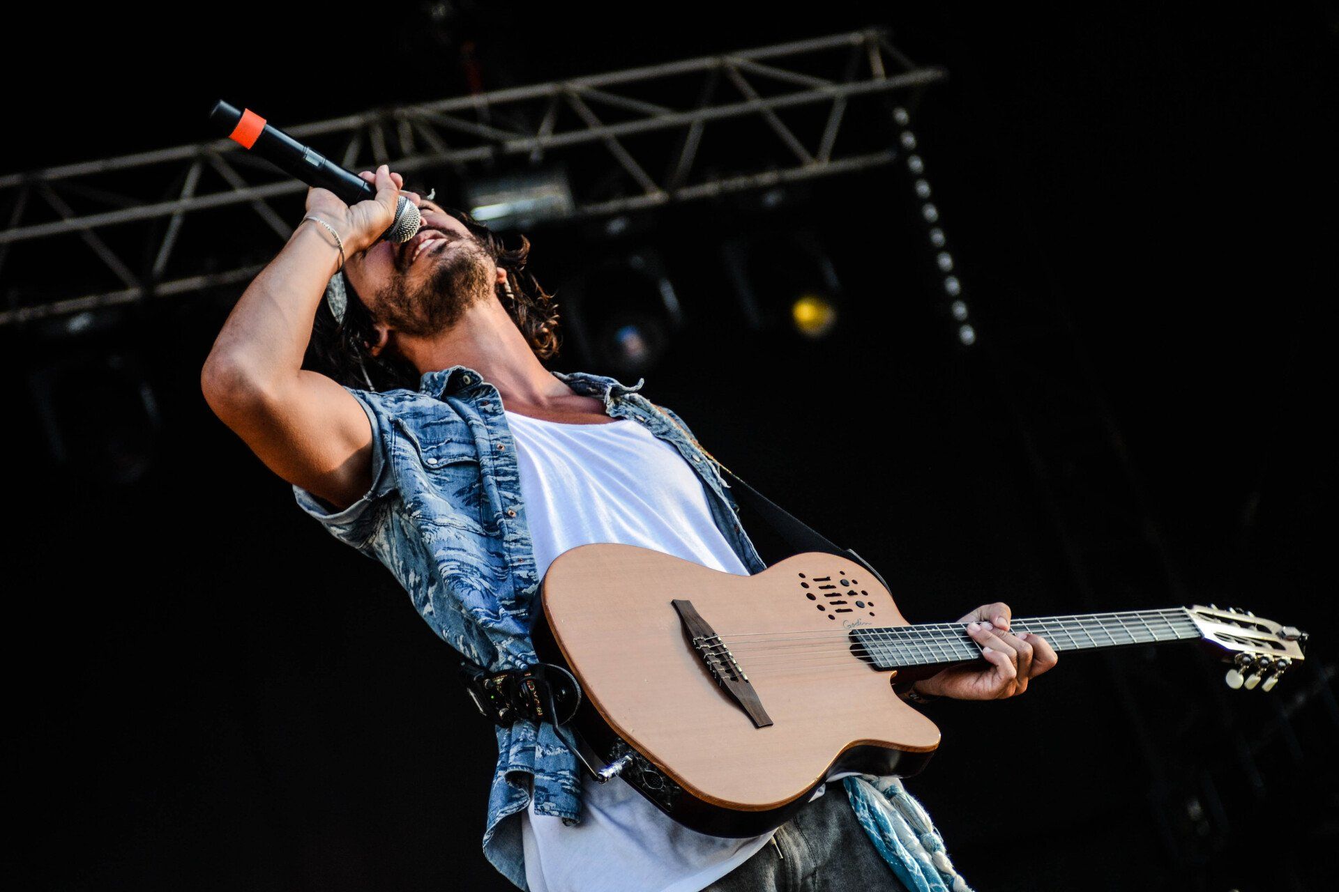 musician signing into a microphone holding a guitar